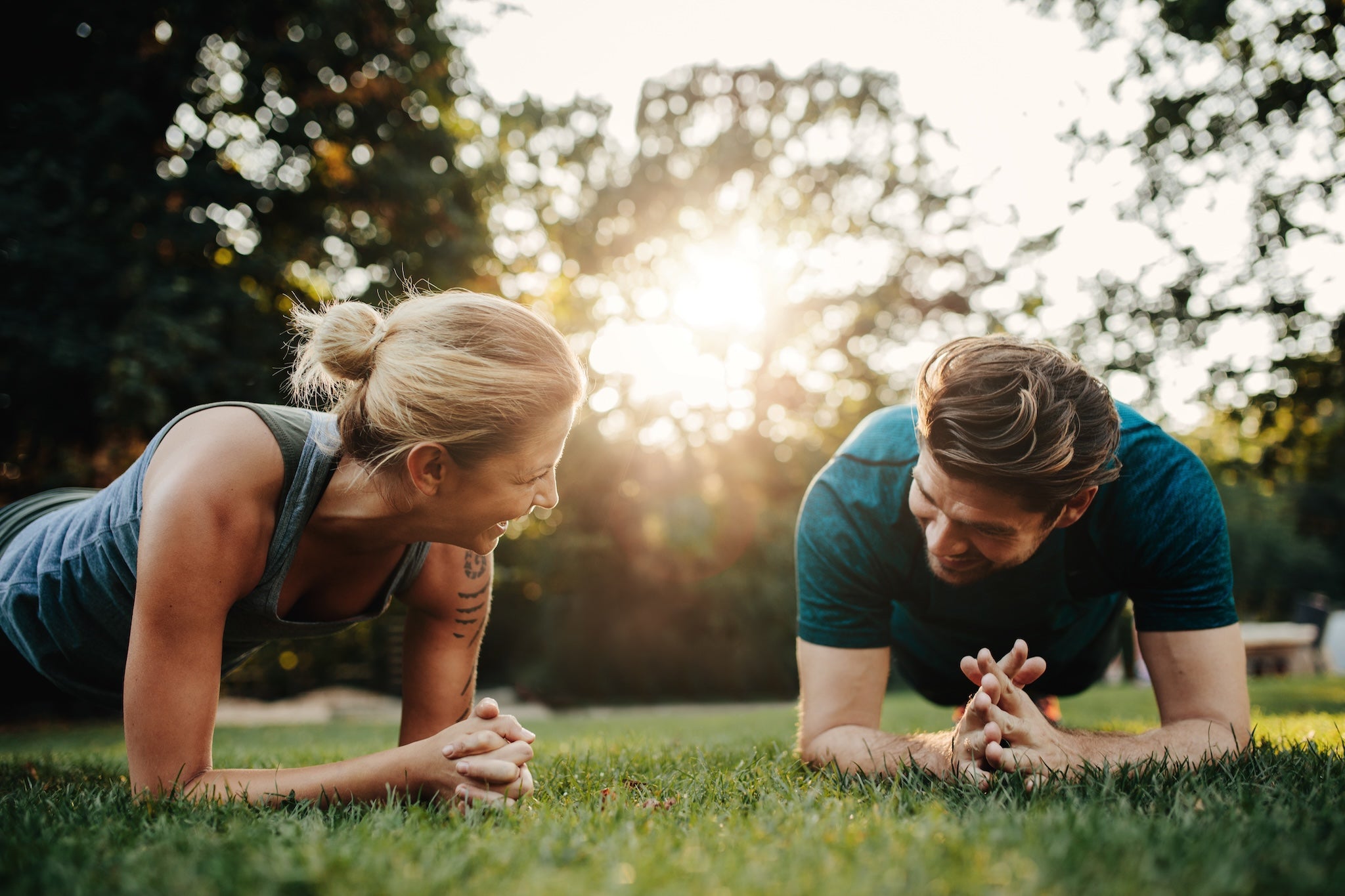 Frau und Mann machen gemeinsam Plank-Übung im Park – Fitness, Training und gesunder Lifestyle mit Spaß an Bewegung.