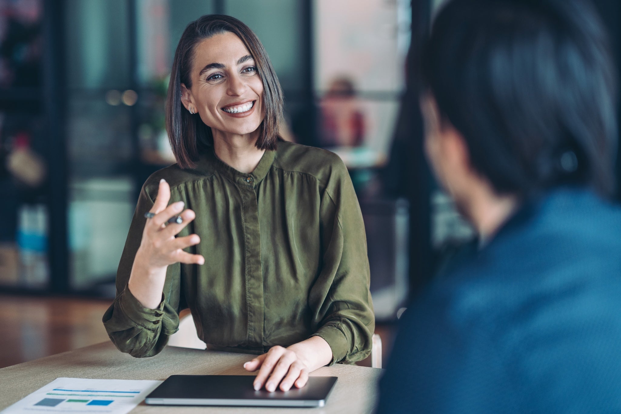 Lächelnde Person in einem Gespräch in moderner Büroumgebung. Symbol für Austausch, Vertrauen und erfolgreiche Zusammenarbeit mit vabon.