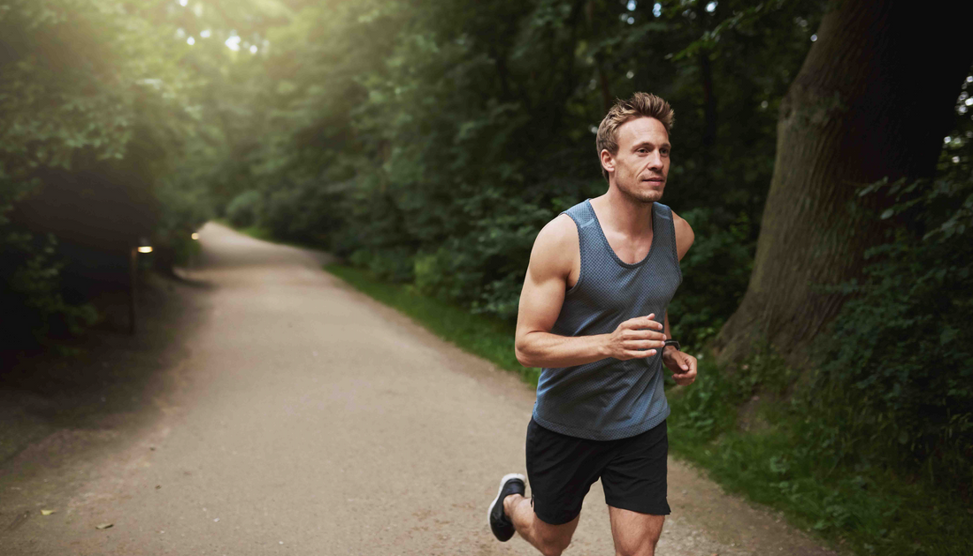 Mann joggt auf Waldweg – gesunder Lifestyle, Fitness und Ausdauertraining in der Natur.