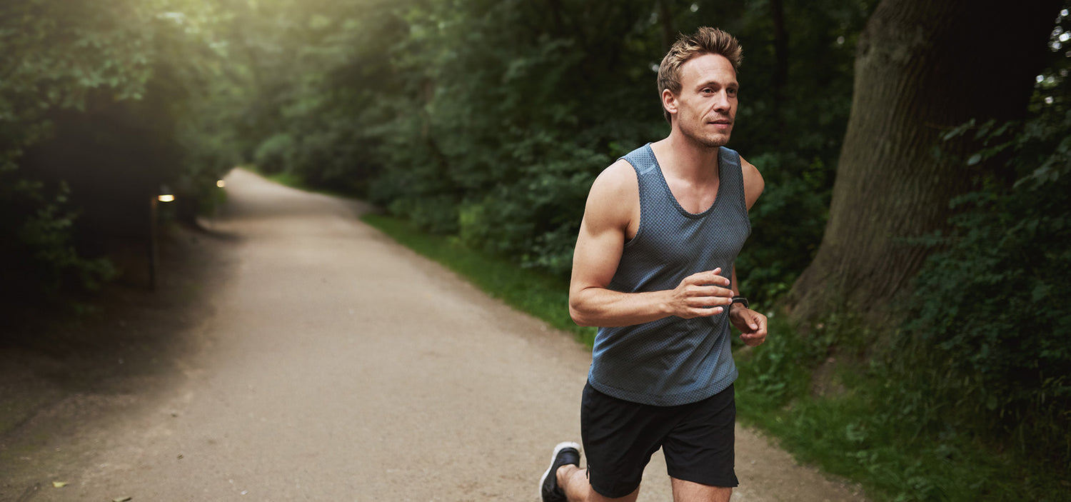 Mann joggt auf Waldweg – gesunder Lifestyle, Fitness und Ausdauertraining in der Natur.