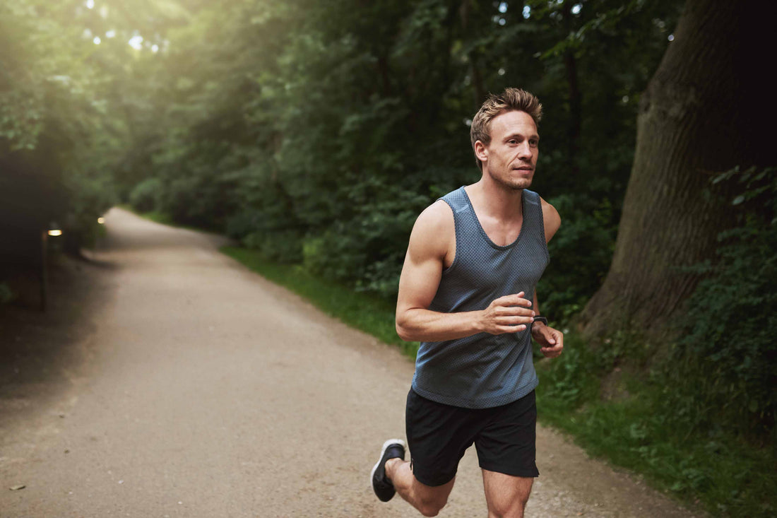 Mann joggt auf Waldweg – gesunder Lifestyle, Fitness und Ausdauertraining in der Natur.
